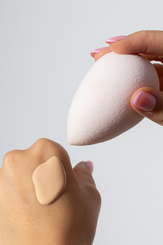 Person Dabbing a Sponge on Hand with Liquid Foundation